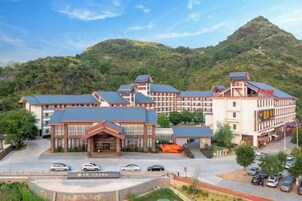 Un hotel con varias construcciones, un estacionamiento y montañas al fondo.