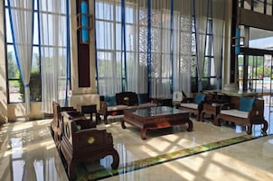 A spacious lobby with a large seating area, a coffee table, and a view through large windows.