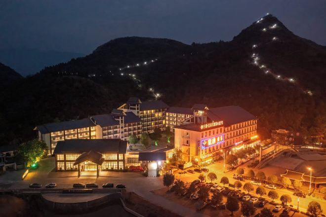 A hotel with multiple buildings, a parking area, and a mountainous backdrop.