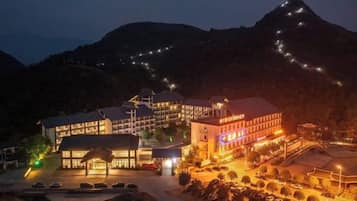 A hotel with multiple buildings, a parking area, and a mountainous backdrop.