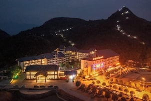 A hotel with multiple buildings, a parking area, and a mountainous backdrop.
