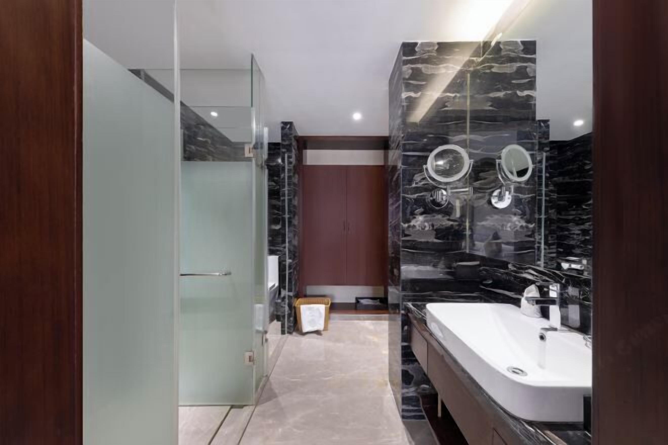 A modern bathroom with a glass shower enclosure, a marble vanity, and a large mirror.