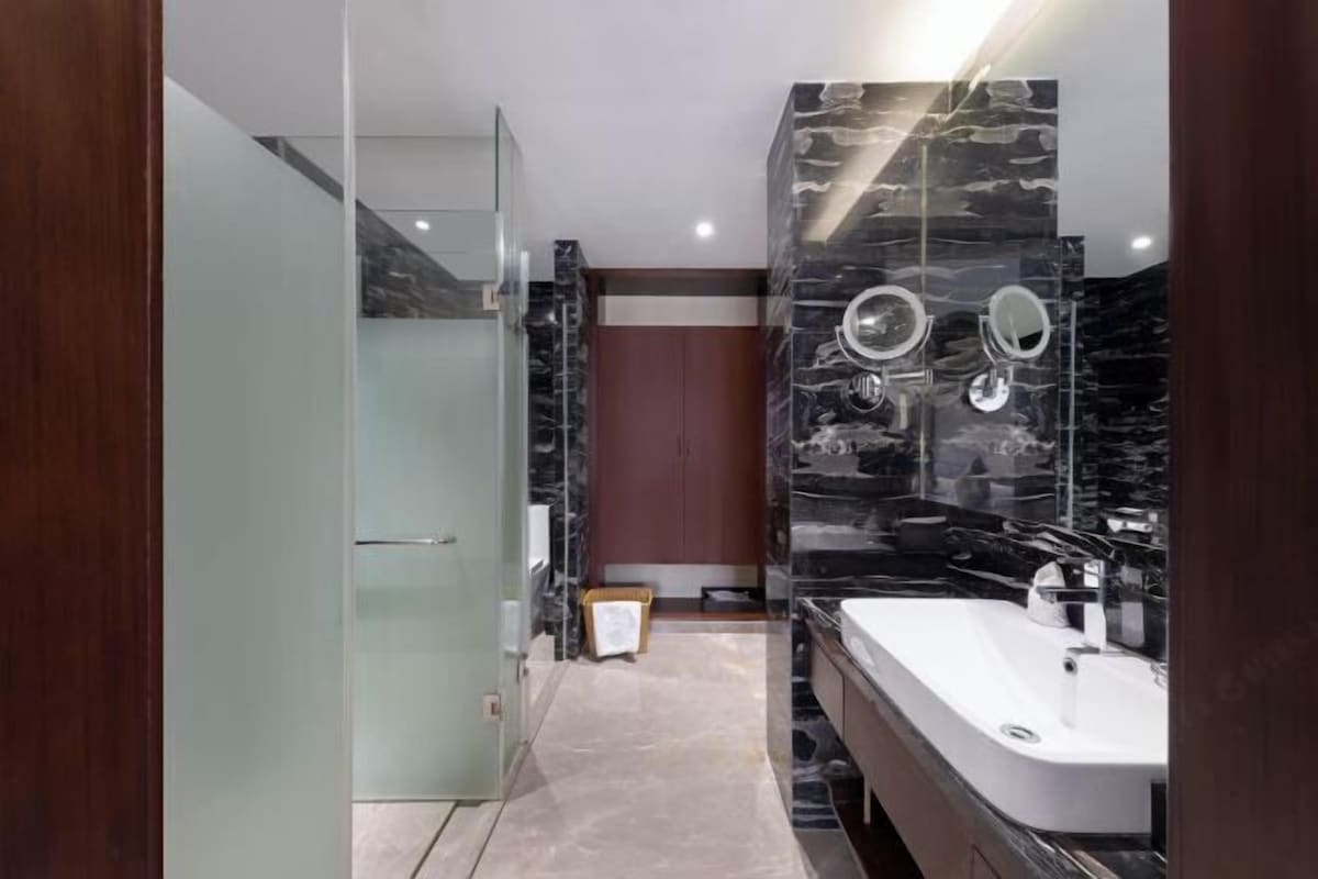 A modern bathroom with a glass shower enclosure, a marble vanity, and a large mirror.