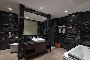 A modern bathroom with a dark marble theme, a large mirror, a white sink, a toilet, and a bathtub. - Jiangyong Hotel (Jiangyong)