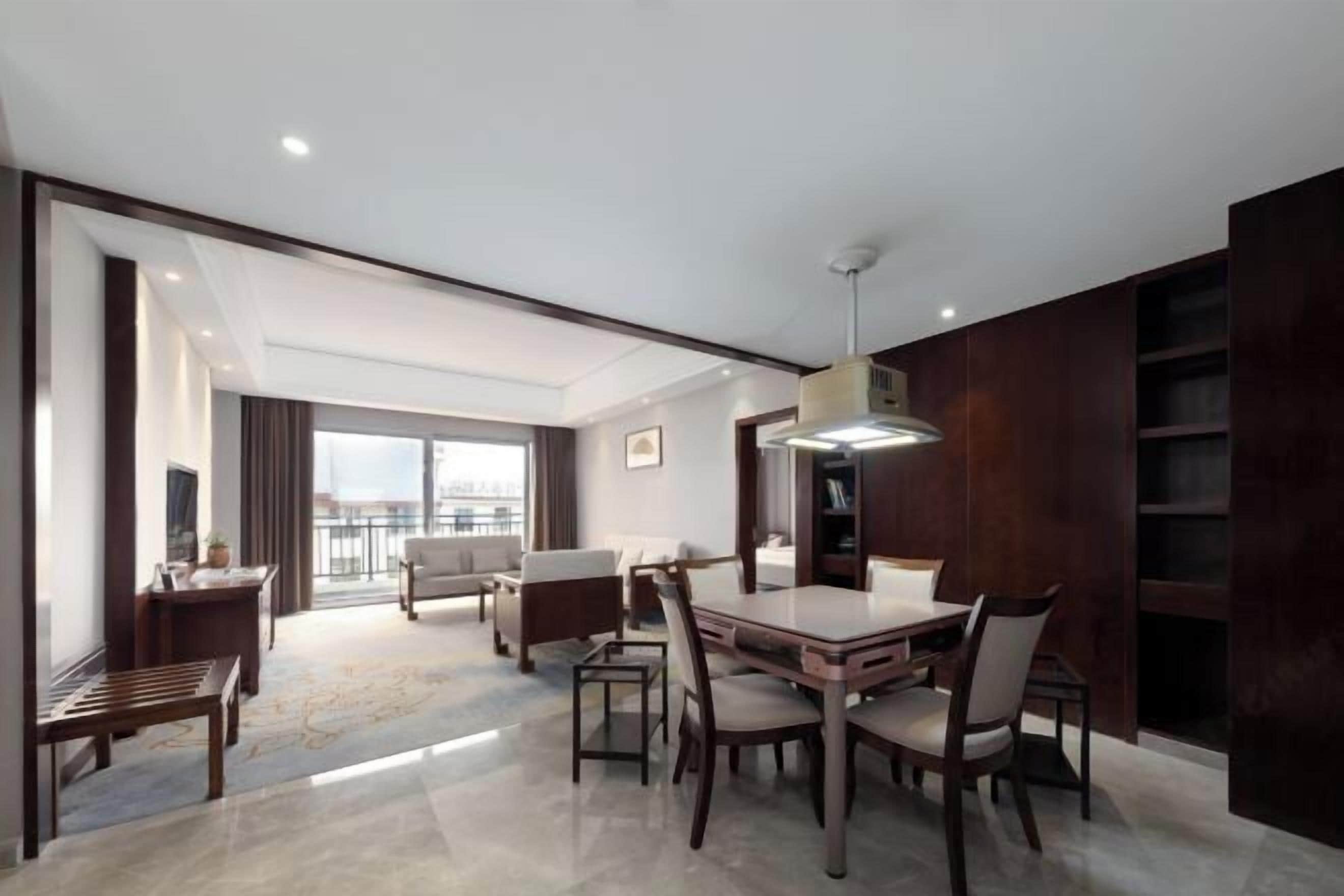 Una habitación de hotel moderna con comedor, un ventanal y vistas a la ciudad.