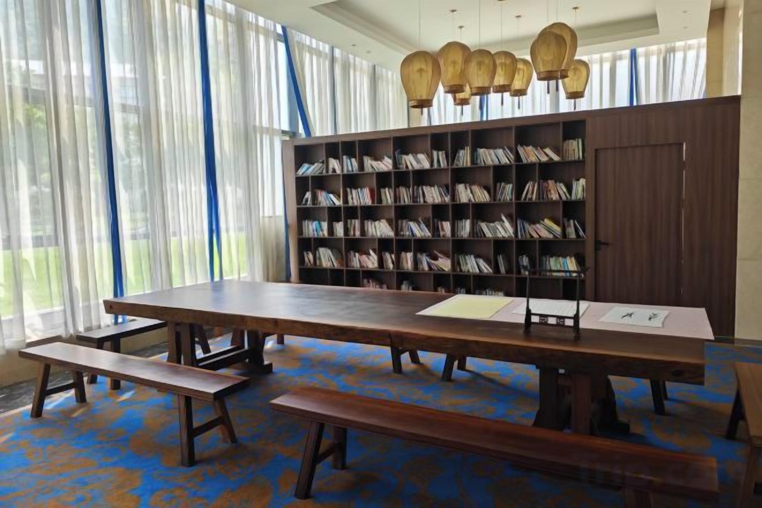 A library with bookshelves, a long table, and benches.