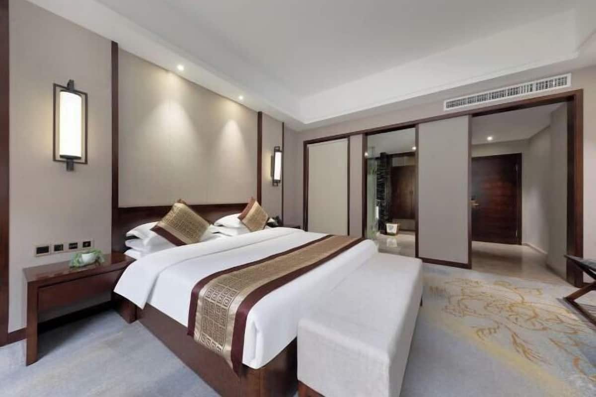 Une chambre d’hôtel avec un grand lit, des tables de chevet, une armoire et un miroir.