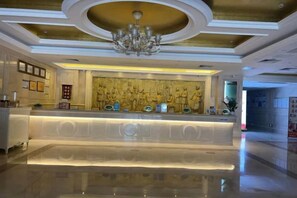 A hotel lobby with a reception desk, a chandelier, and a wall with decorative panels. - Vienna Hotel (Xinyi Jiaoyucheng River View) (Xinyi)