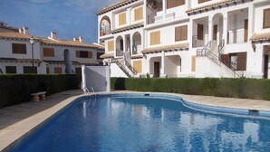Una piscina con un edificio blanco al fondo.