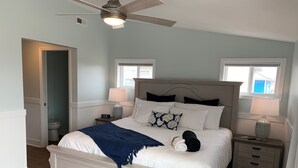 Una camera da letto con un letto, comodini, una ventola a soffitto e una finestra.