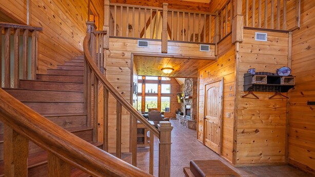 A wooden interior with a staircase, a fireplace, and a dining area. - Gated Hilltop Luxury Lodge on 100 acres - Relax and Enjoy AMAZING VIEWS (Smithville)