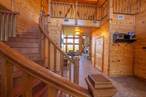 Un intérieur en bois avec un escalier, une cheminée et un coin repas.