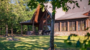A rustic cabin with a stone foundation, large windows, and a covered porch. - Gated Hilltop Luxury Lodge on 100 acres - Relax and Enjoy AMAZING VIEWS (Smithville)