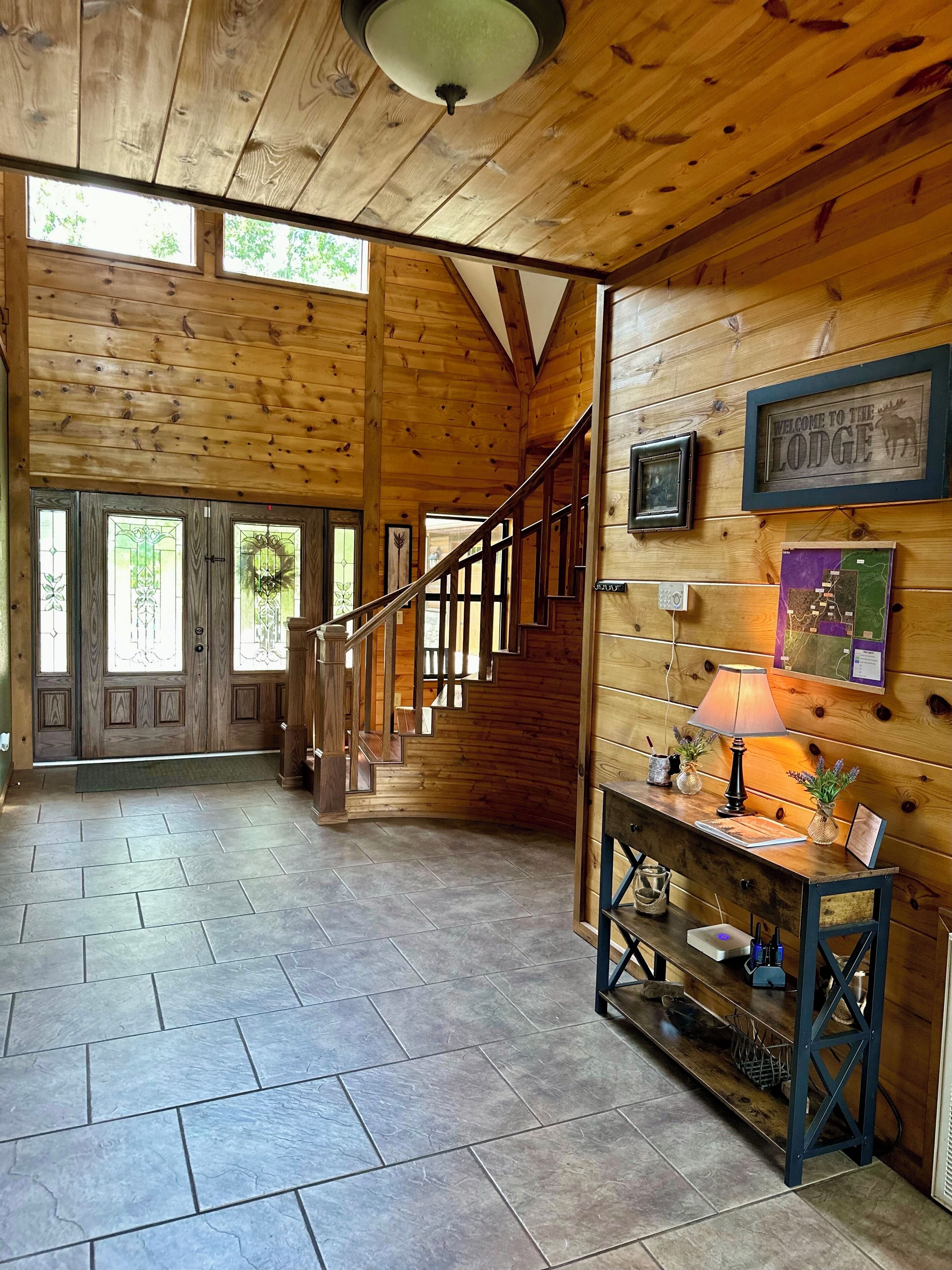A wooden interior with a staircase, a reception desk, and framed welcome signs.