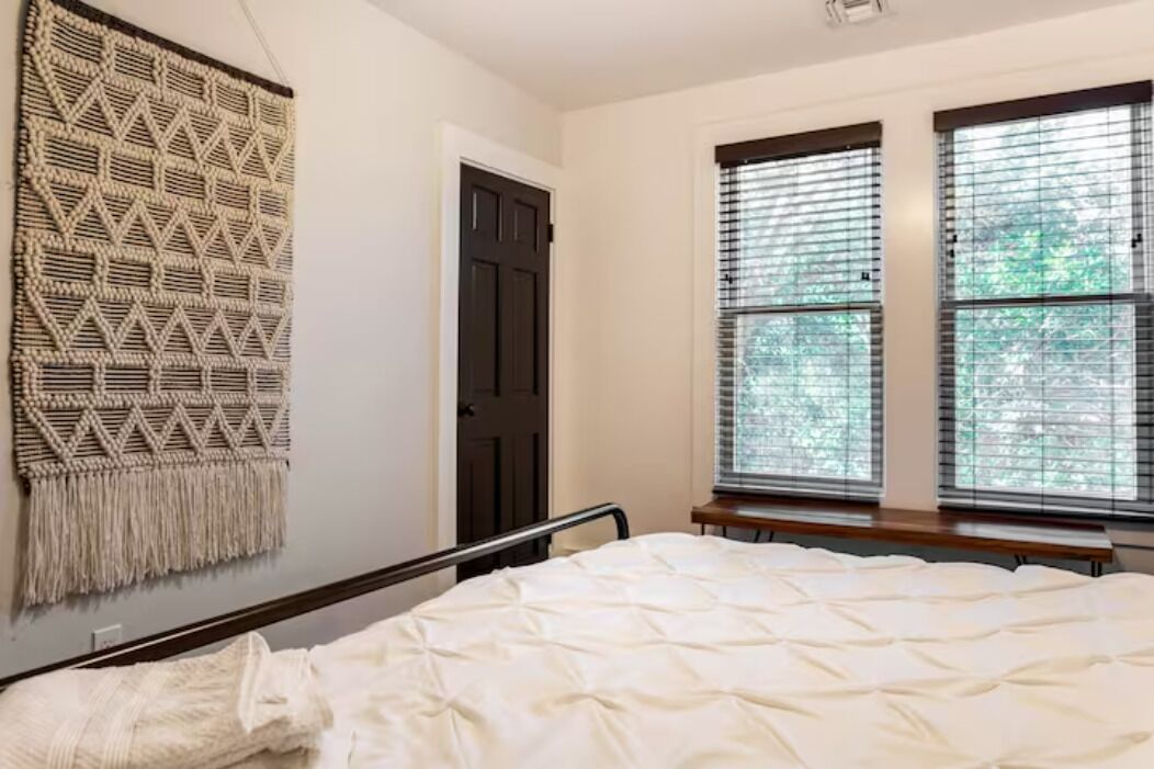Un dormitorio con cama, un tapiz en la pared y una ventana con persianas.