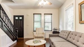 A living room with a sofa, a chair, a coffee table, and a ceiling fan. - Northfork Townhouse walk to all (Greenport)