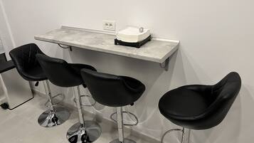 A bar area with three black bar stools and a countertop with a coffee machine.