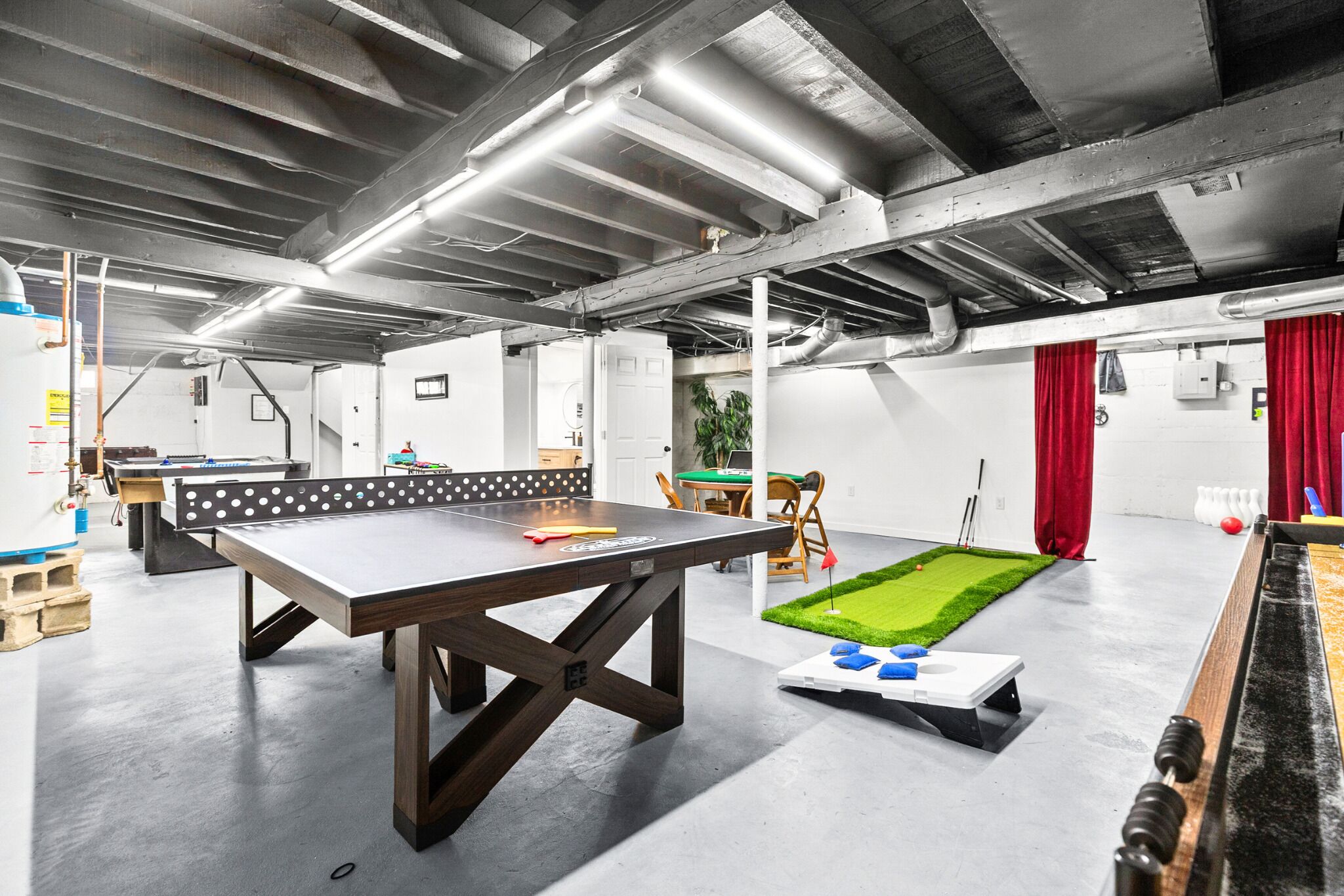 Ett rymligt inomhusområde med ett bordtennisbord, ett fotbollsspel och en liten gräsyta.