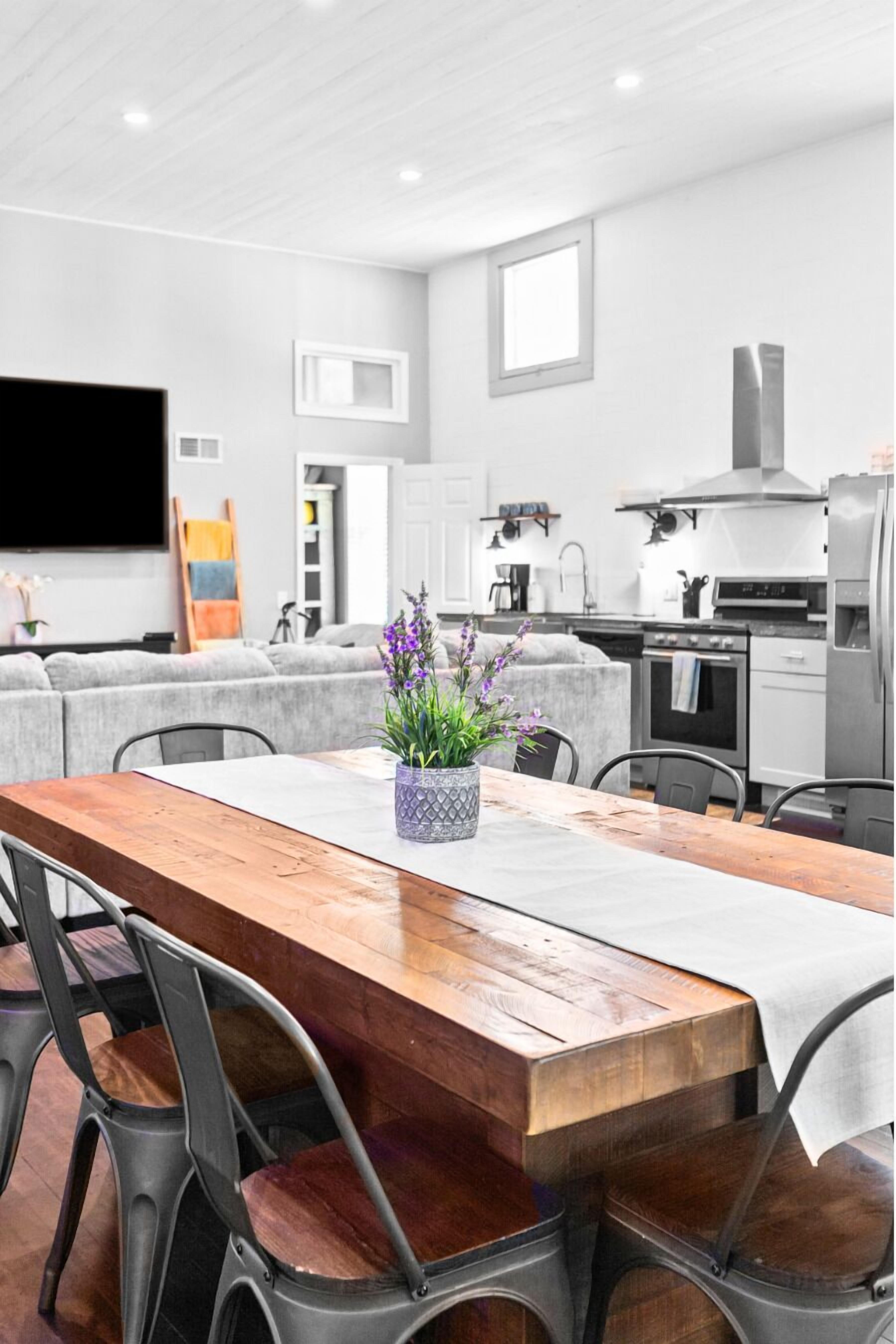 Una cocina moderna con una mesa de comedor de madera, sillas grises y una planta en maceta.