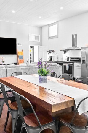 Una cocina moderna con una mesa de comedor de madera, sillas grises y una planta en maceta.
