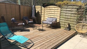 A wooden deck with outdoor furniture including a blue chair, a sofa, and a meditation statue. - Bigazen - Family house sleeps 8 (Biganos)