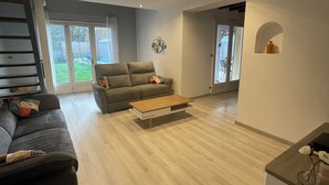 A modern living room with a sofa, a coffee table, and a staircase. - Bigazen - Family house sleeps 8 (Biganos)