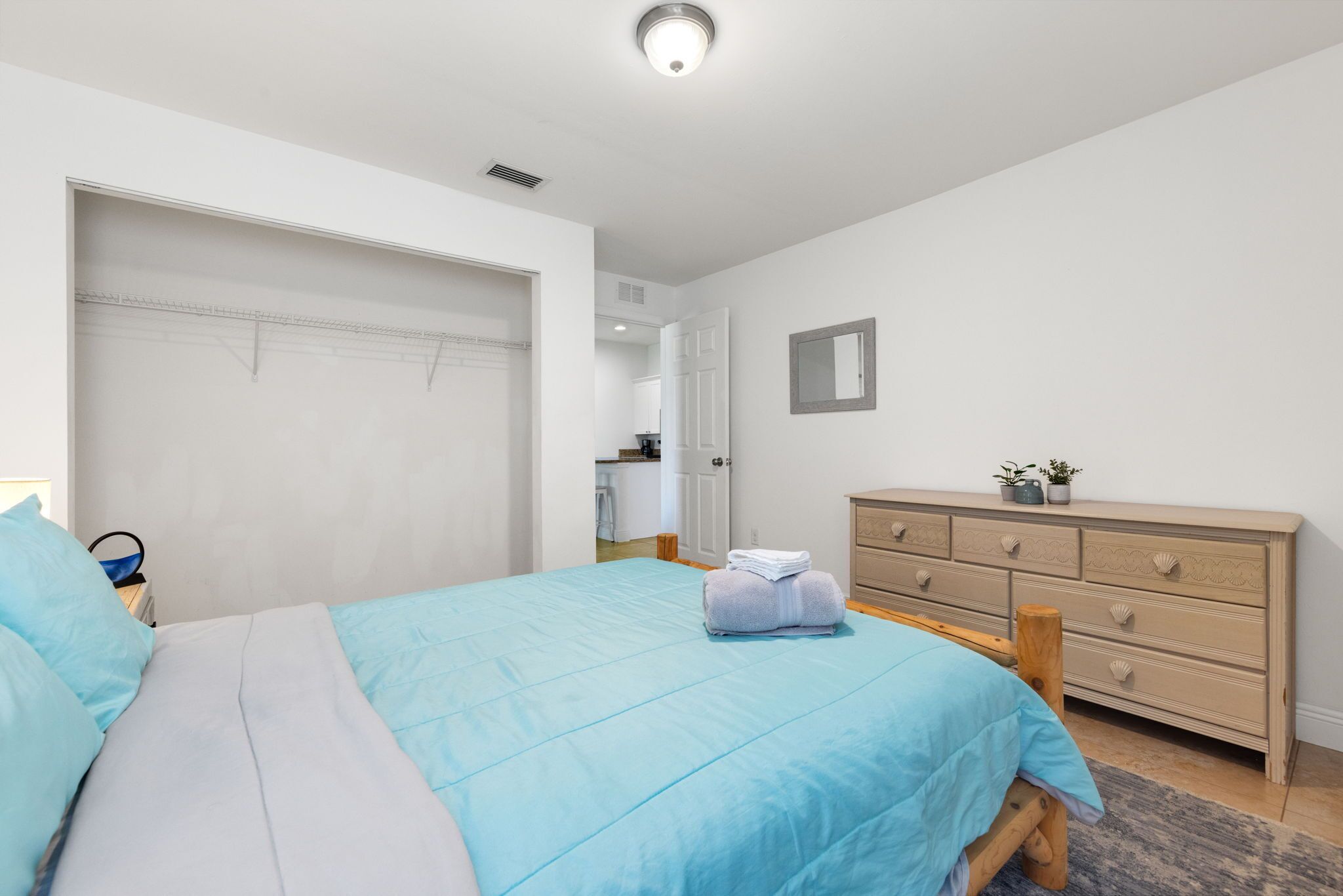 A bedroom with a bed, a dresser, and a door leading to a bathroom.