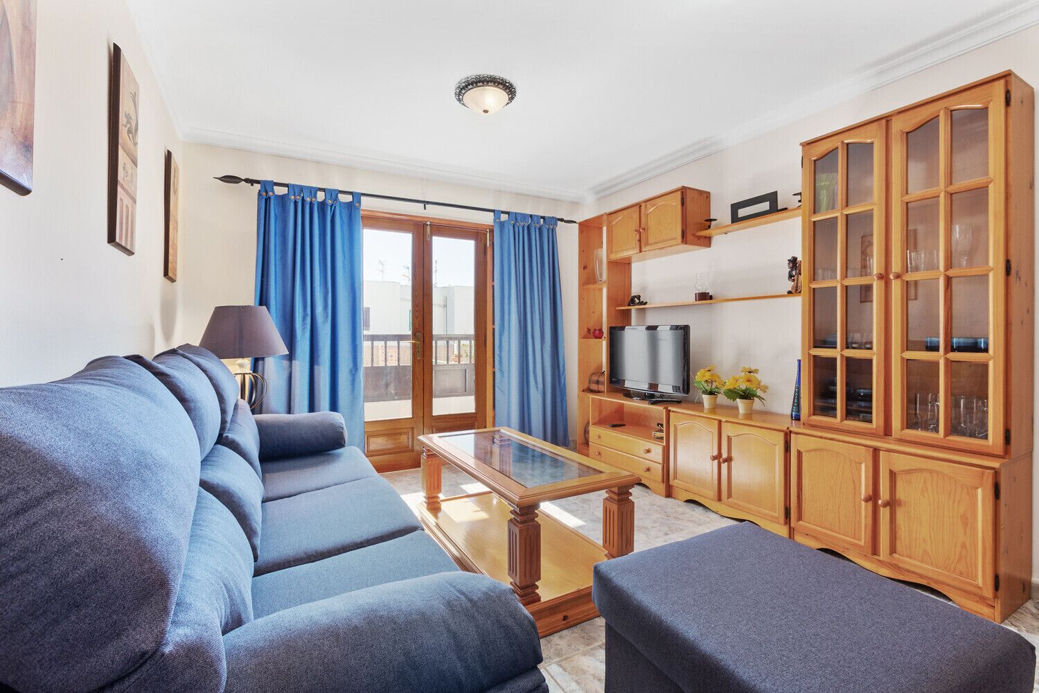 A living room with a sofa, a coffee table, a television, and wooden cabinets.