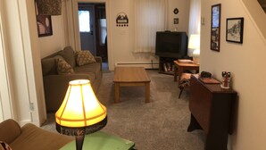 Un salon avec un canapé, une table basse, un téléviseur et une lampe.