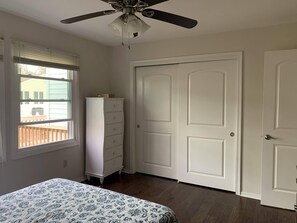 Un dormitorio con cama, cómoda, ventilador de techo y puerta.