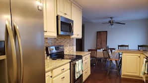 Una cocina equipada con refrigerador, microondas, estufa y gabinetes de madera.