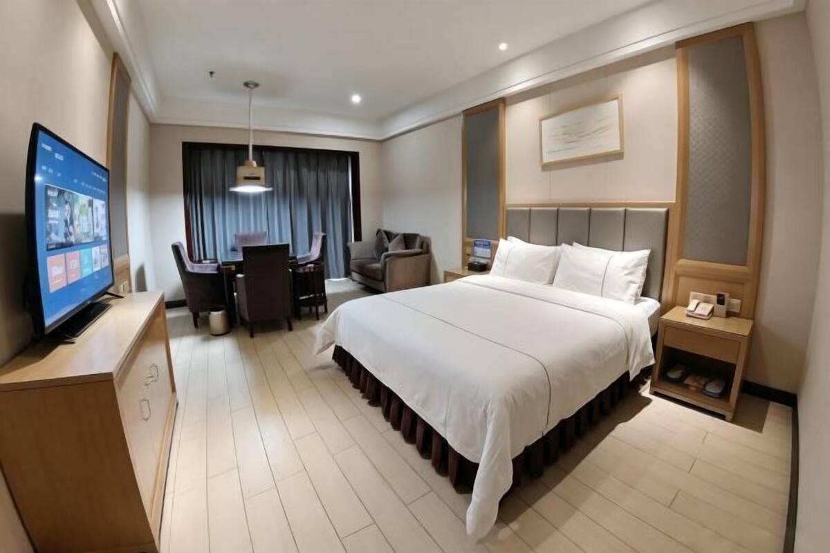 A hotel room with a bed, a desk, a chair, a television, and a nightstand.