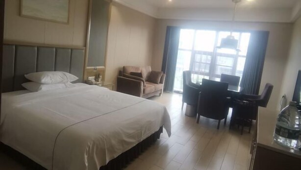 A hotel room with a large bed, a desk, and a chair. - Xiangrui Hotel (Changde)