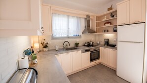 Una cocina moderna con armarios blancos, un lavamanos de acero inoxidable, horno empotrado y refrigerador blanco.