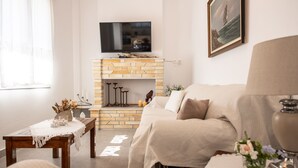 Una sala de estar con chimenea, un sofá, un televisor sobre la chimenea y un cuadro en la pared.