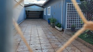 A covered patio area with a tiled floor, a garage door, and potted plants.