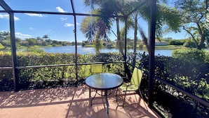 A covered outdoor area with a table and chairs, overlooking a lake and surrounding greenery.