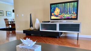 A living room with a television displaying an animated show, a vase, and a tissue box on a table.