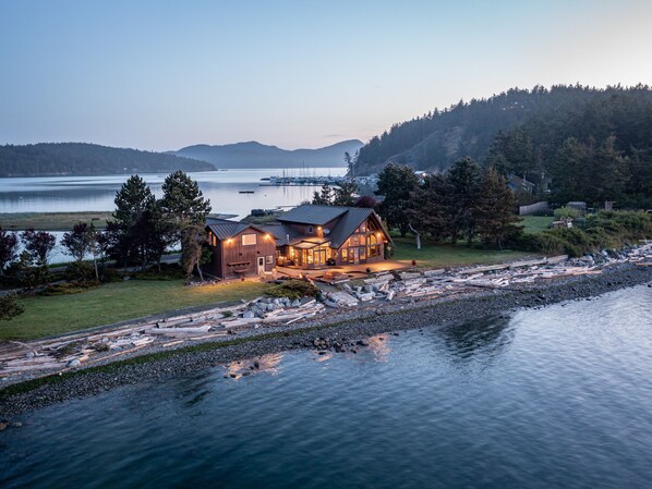 A cabin with a large porch and a view of the water.