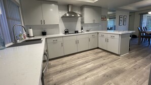 Une cuisine moderne avec des armoires blanches, une hotte de cuisinière en acier inoxydable et un plancher en bois.