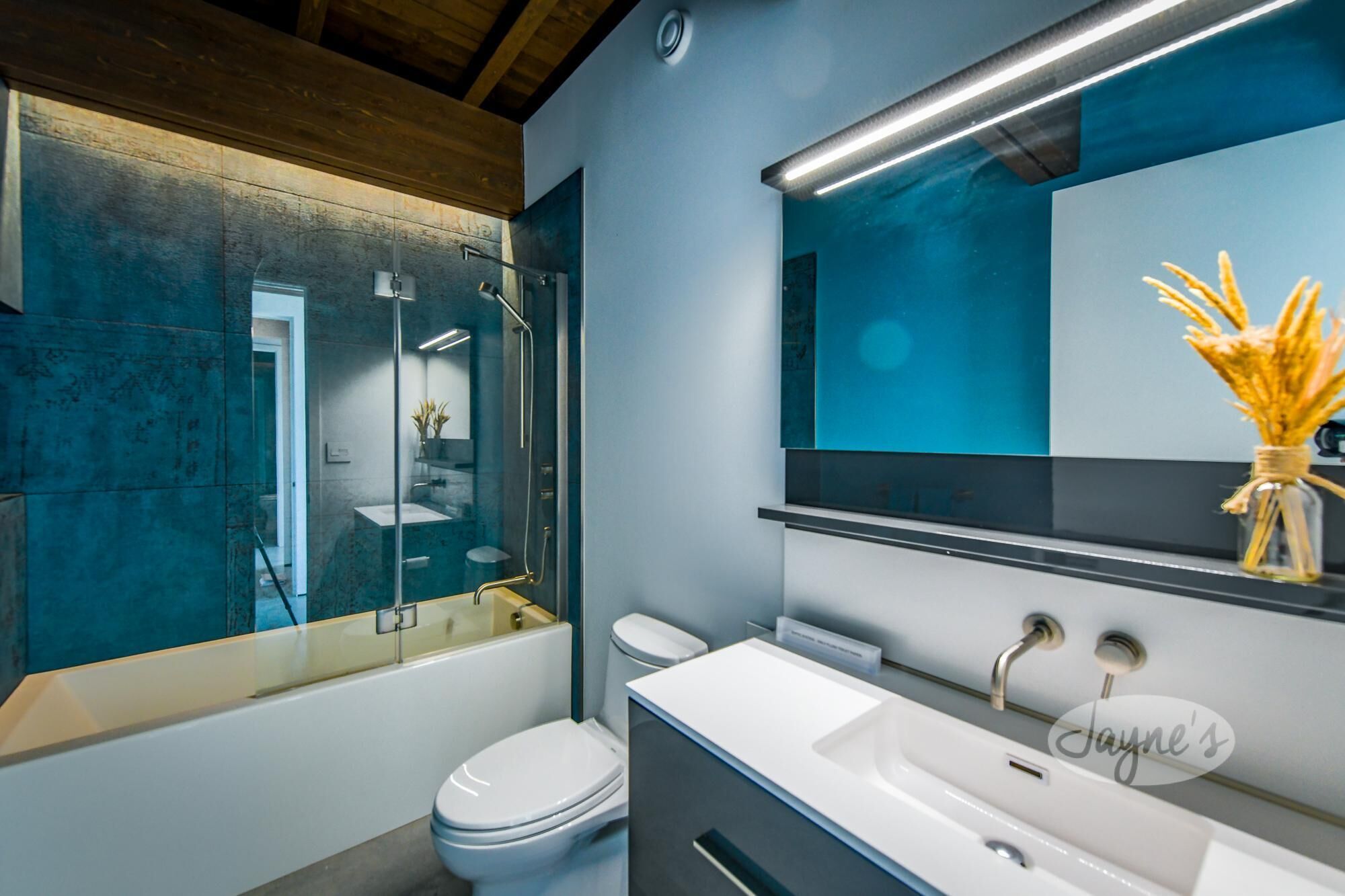 Un baño moderno con ducha envuelta en vidrio, inodoro blanco y tocador con espejo.