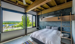 Een moderne slaapkamer met een groot raam, een stapelbed en uitzicht op groen.