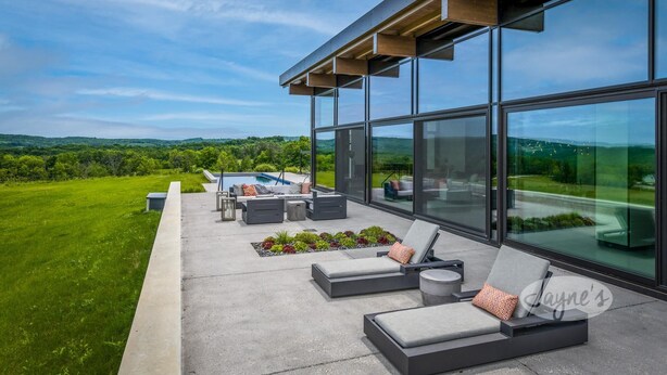 A modern outdoor lounge area with a pool, large windows, and a view of the countryside. - 5bdrm 7bath modern oasis in Creemore! Pool! Hot Tub! Sauna! Podcast Media Rm! (Creemore)
