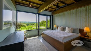 A bedroom with a large bed, a desk, and a view of greenery. - 5bdrm 7bath modern oasis in Creemore! Pool! Hot Tub! Sauna! Podcast Media Rm! (Creemore)