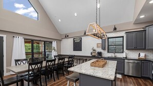 Una cocina moderna con una isla grande, piso de madera oscura y vistas al exterior.