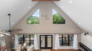 Un espacioso dormitorio tipo loft con techo inclinado, ventanas amplias y vistas al exterior.