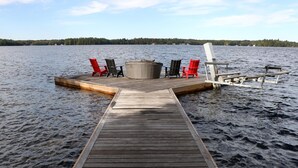 Une jetée en bois s’avançant dans un lac, avec plusieurs chaises et un banc.