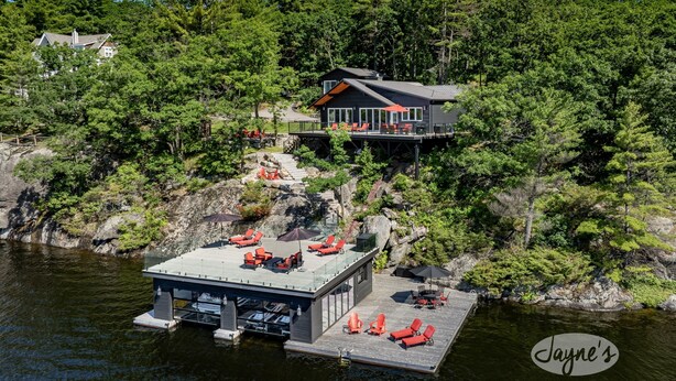 A lakeside cabin with a dock, outdoor seating, and a forested backdrop. - SW Exposure at this 4 bdrm, 3 bath cottage with stunning views of Lake Muskoka! (Gravenhurst)