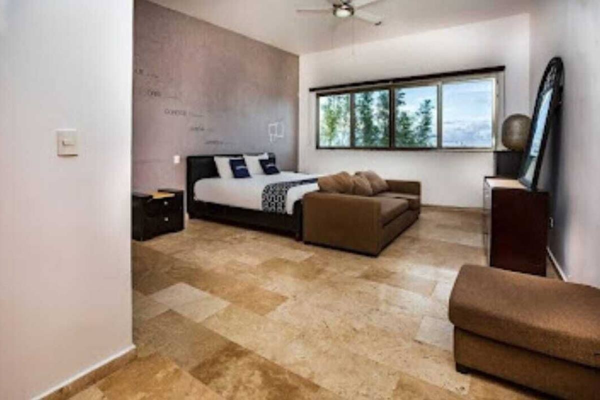 Ein Schlafzimmer mit Bett, Sofa, Fenster und Deckenventilator.