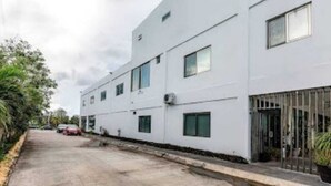 A modern building with a flat facade, multiple windows, and a gated entrance.
